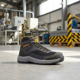 Black safety boot with yellow accents on a concrete floor in an industrial setting
