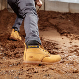 Worker wearing Caterpillar Powerplant S3 wheat safety boots digging on muddy construction site