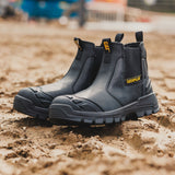 Caterpillar Striver XL S7 black dealer boots pair on muddy construction site showing waterproof leather