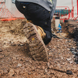 Caterpillar Striver XL S7 tan safety boot sole grip on gravel with worker kneeling on site
